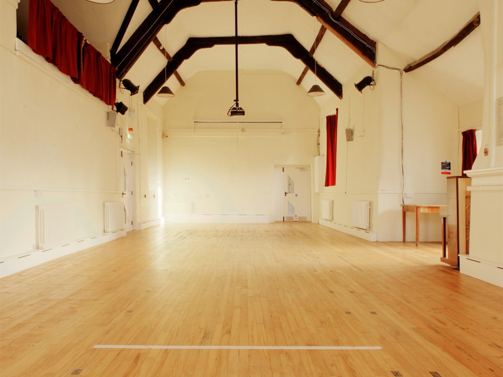 Spacious interior of the hall, with wall mounted screen and projector.